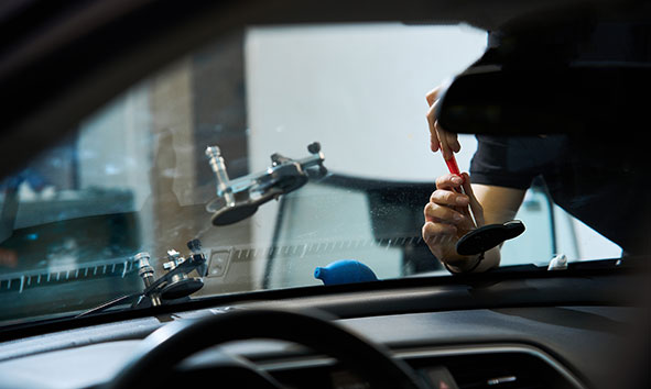Mobiler Autoglas-Techniker repariert eine Windschutzscheibe vor Ort