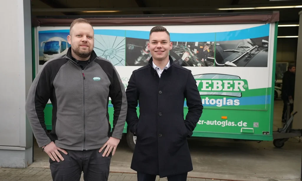 Zwei Mitarbeiter von WEBER Autoglas vor einem Firmenfahrzeug
